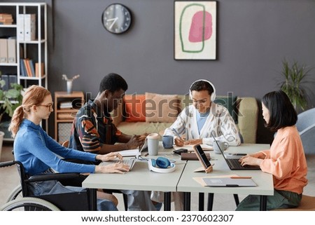 Side view portrait of diverse young team working together at common table in modern office Royalty-Free Stock Photo #2370602307