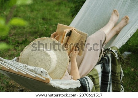 Harmony in a backyard haven a woman, a book, a hammock. A tranquil snapshot of slow living, a joyful escape from the urban hustle Royalty-Free Stock Photo #2370611517