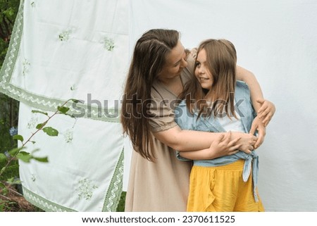mom and her little girl hug tightly among fresh laundry. This scene captures the essence of nurturing relationships, vital in fostering a child's sense of security and belonging. Royalty-Free Stock Photo #2370611525