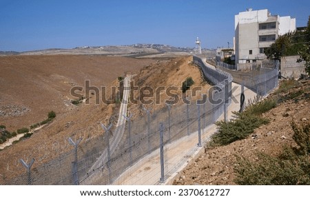 View on Lebanon as seen from Ghajar, also Rhadjar, an Alawite-Arab village located on border between Lebanon and Golan Heights of Israel. Barbed wire at the border. Large lebanon village at background Royalty-Free Stock Photo #2370612727