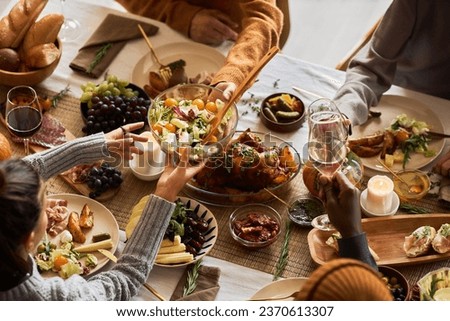 Multiethnic group of people at festive dinner table celebrating Thanksgiving together and enjoying rustic roasted dishes, copy space Royalty-Free Stock Photo #2370613307