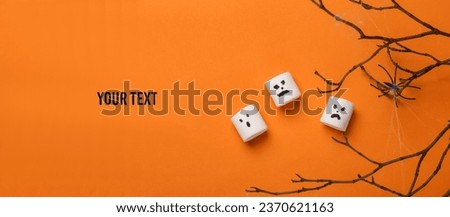 Halloween decor, marshmallows with faces and dry branch with spider on orange background.Top view. Flat lay. Copy space