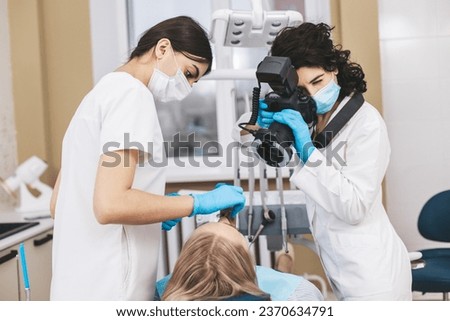 Female dentist with camera making shots of patient's smile