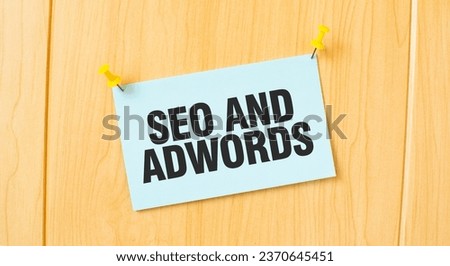 SEO AND ADWORDS sign written on sticky note pinned on wooden wall