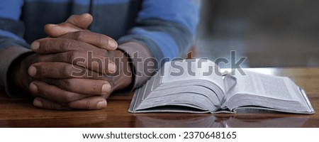 black man praying to god with bible with background with people stock image stock photo