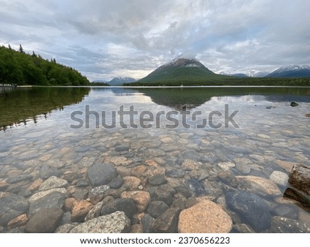 Clear lake with rock bottom. Hardenburg Bay on Lake Clark, Alaska. Tanalian Mountain reflected on water. Port Alsworth in Lake Clark National Park and Preserve.  Royalty-Free Stock Photo #2370656223