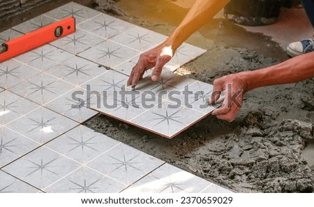 Floor tiles installation. Ceramic tiles and tools for tiler. Home improvement, renovation - ceramic tile floor adhesive, trowel with mortar, level. Royalty-Free Stock Photo #2370659029