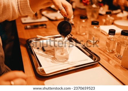 Pouring melted wax into glass. Set for crafting candle on metal tray. Master class of making candles. Beautiful female hands hold metal jug with wax. Creative occupation of making trendy diy candles. Royalty-Free Stock Photo #2370659523