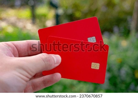 Two red bank cards in his hand. The hand holds two blank credit cards (no inscriptions).  Royalty-Free Stock Photo #2370670857