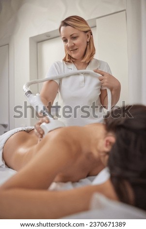 weight loss, Fighting overweight, anti cellulite massage. Young woman is taking part in beauty consultations, body shaping within professional beauty salon, masseur is using vacuum roller massage