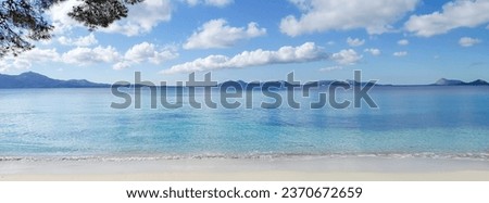 A picturesque view of Formentor Beach showcases its clear, transparent waters that stretch to the horizon, where distant mountains provide a majestic backdrop to this serene Mallorcan paradise.

 Royalty-Free Stock Photo #2370672659