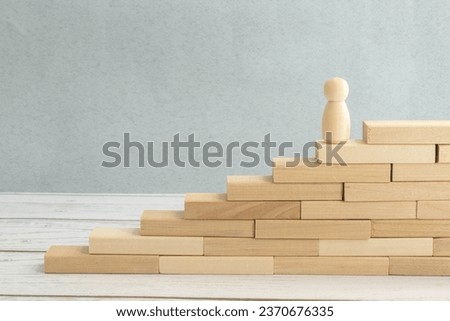 silhouette of an office worker with a suitcase climbs the stairs. gears on a wooden background.