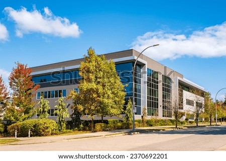 Architectural facade building with of glass elements. Exterior of a modern industrial building. Modern Business Gray Contemporary Building in Urban Street Setting. Corner Business Building Royalty-Free Stock Photo #2370692201