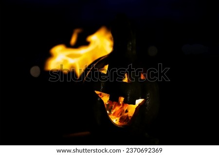 A pumpkin with fire inside and around it on a dark night. 