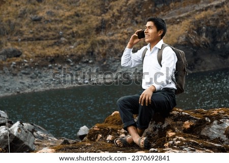 A photo of a Caucasian student peasant boy using a smartphone during advertising in a park, Quechua native man with cell phone, lifestyle, communication Royalty-Free Stock Photo #2370692841