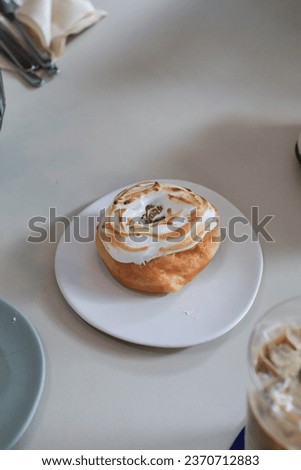 Lemon meringue donut on white plate.  Sweet summer dessert. Minimal concept. Doughnuts and bakery.