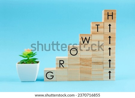 GROWTH word on wood cubes stacking as step up and plant pot on blue background, Business investment concepts for growth success.