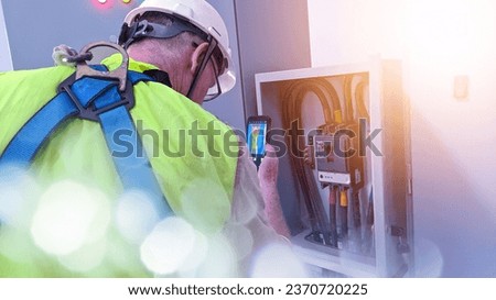 Technician Engineering use thermal imaging camera to check temperature of instalation inverter solar panel in factory
with shiny light and space  text.