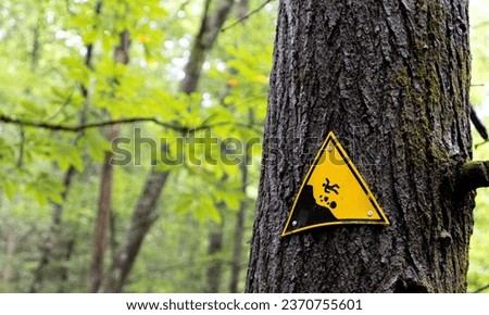 A caution sign on a tree in the woods