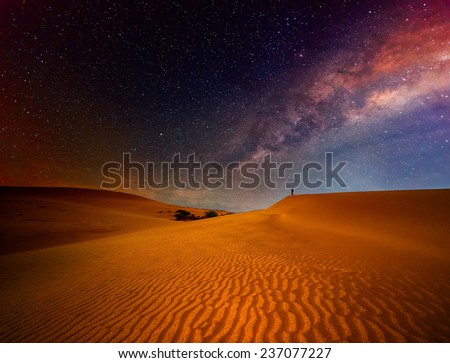 Tourist with backpack standing on top of a mountain and enjoying night sky view with stars.