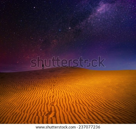 A traveller is going among sandy dunes under the starry sky