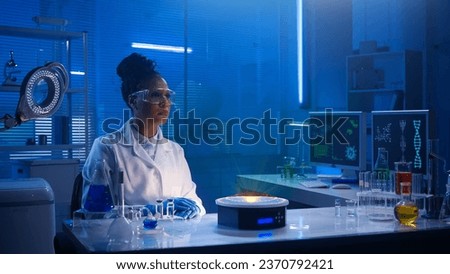 Medium-sized photo capturing a dark-skinned female scientist wearing glasses and lab coats sitting in a laboratory, researching a hologram, your graphics.