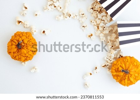 Black and white striped boxes with popcorn and decorative pumpkins. Entertainment concept. Halloween movie night with popcorn. 