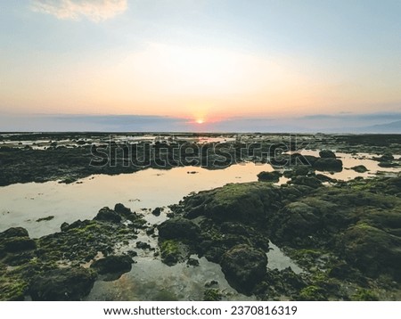 the sun is setting over a body of water at Sumbawa island , sunset panorama, rock pools, ultra wide angle horizon, panoramic anamorphic, panoramic photography,