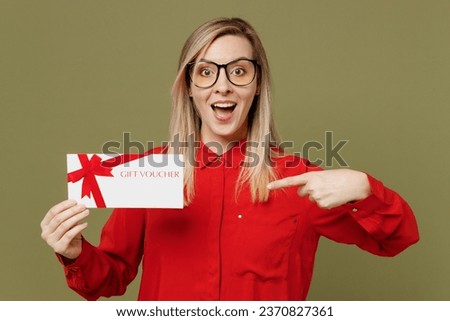 Young happy fun woman she wear red shirt casual clothes glasses hold point finger on gift certificate coupon voucher card for store isolated on plain pastel green background studio. Lifestyle concept Royalty-Free Stock Photo #2370827361