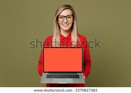 Young smiling fun happy IT woman wears red shirt casual clothes glasses hold use work on laptop pc computer with blank screen workspace area isolated on plain pastel green background studio portrait
