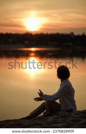 Dark Silhouette of a Woman against the backdrop of a golden sunset, sand, water, river