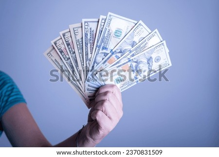 Female hand holding dollar bills on blue background. Concept of money and finance. Economic crisis