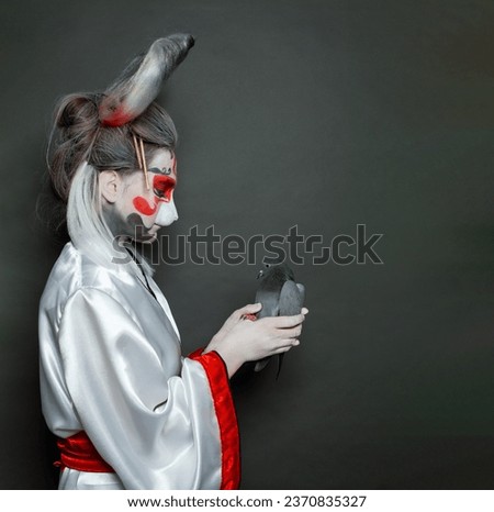 Fairy tale character. Woman hare holding pigeon bird on black background. Halloween makeup costume