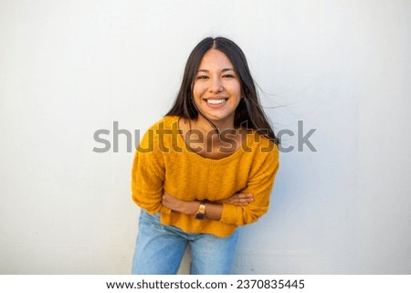 Portrait smiling young woman with arms crossed by white background