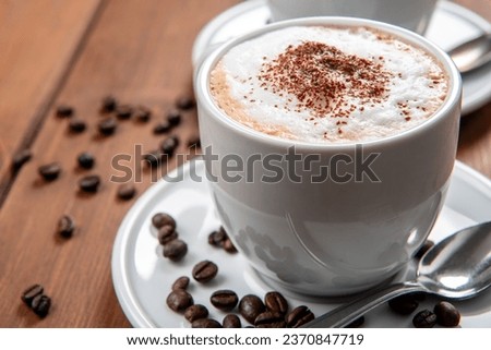 Cup with hot cappuccino with foam and cocoa powder, italian breakfast  Royalty-Free Stock Photo #2370847719