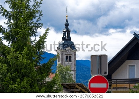 Scenic view of rural Slovenian village of Zabnica with no entry sign and church tower in the background on a cloudy summer day. Photo taken August 10th, 2023, Zabnica, Kranj, Slovenia.