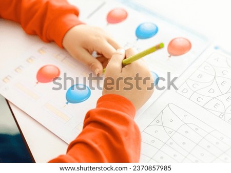 A creative kid coloring the shapes in coloring book with pencil. Coloring Book Education Talent Concept.