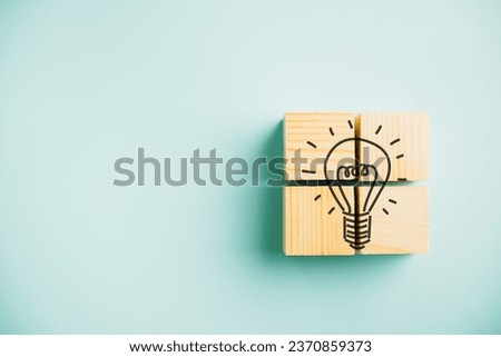 Creative concept represented by wooden cube with light bulb icon on blue background. Teamwork and brainstorming session for generating new business ideas and selecting the best solutions. Royalty-Free Stock Photo #2370859373