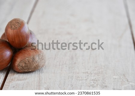 Several fresh chestnuts on the white wooden table.
