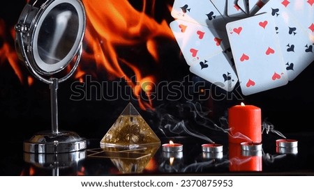 Burning candles, taro cards on black background. Flame reflecting in mirror. Magic or spiritualism ritual. Mystical atmosphere of fortune telling.