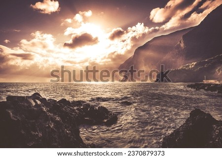 View of the coast of Madeira. The sun breaks through the clouds. Warm color photo.