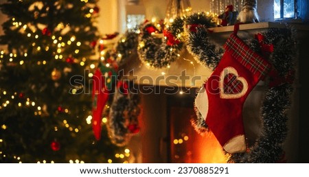 Empty Shot Depicting the Magic of Holidays on a Peaceful Snowy Christmas Eve: Close Up on Decorated Fireplace with Stockings Next to a Christmas Tree. Green and Red Garlands, Ribbons and Lights