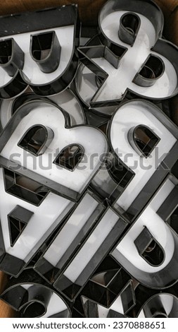 The photo of a collection of 3D fonts made from acrylic that will soon be installed on the roof wall in the afternoon by a sign installation artist in black and white looks very 3D.