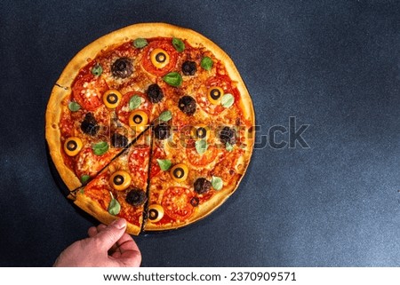 Halloween creative food. funny monster pizza decorated with creepy eyes, on black table background with Halloween party decoration top view copy space