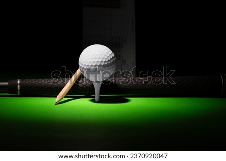 Golf Ball Pencil and Club Handle grip with score card in the distance,  golf equipment on a black and green background
