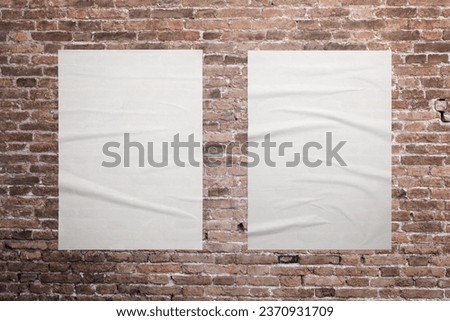 Two blank, white A3 posters are glued to the brick wall. Ideal surfaces for mockup graphic design promotion Royalty-Free Stock Photo #2370931709