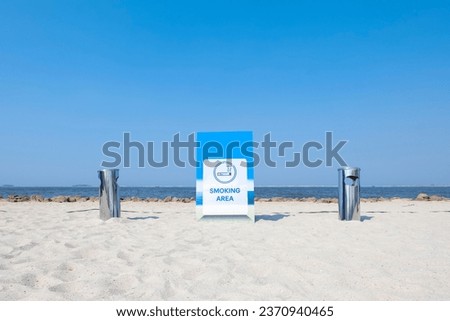Smoking area sign and trash bin at the white sand beach.