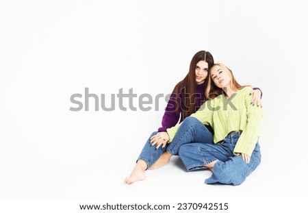 lifestyle, fashion and people concept: Two young female friends sitting on the floor together.