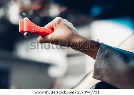 Woman use Safety Hammer and Seatbelt Cutter in Cars, break glass When emergency. In case of emergency on car safety red hammers to break the grass window.	