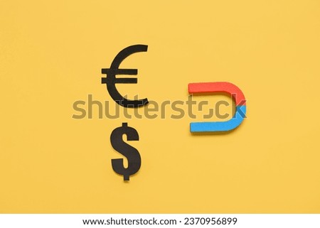 Magnet with dollar and euro signs on yellow background. Attracting investments concept